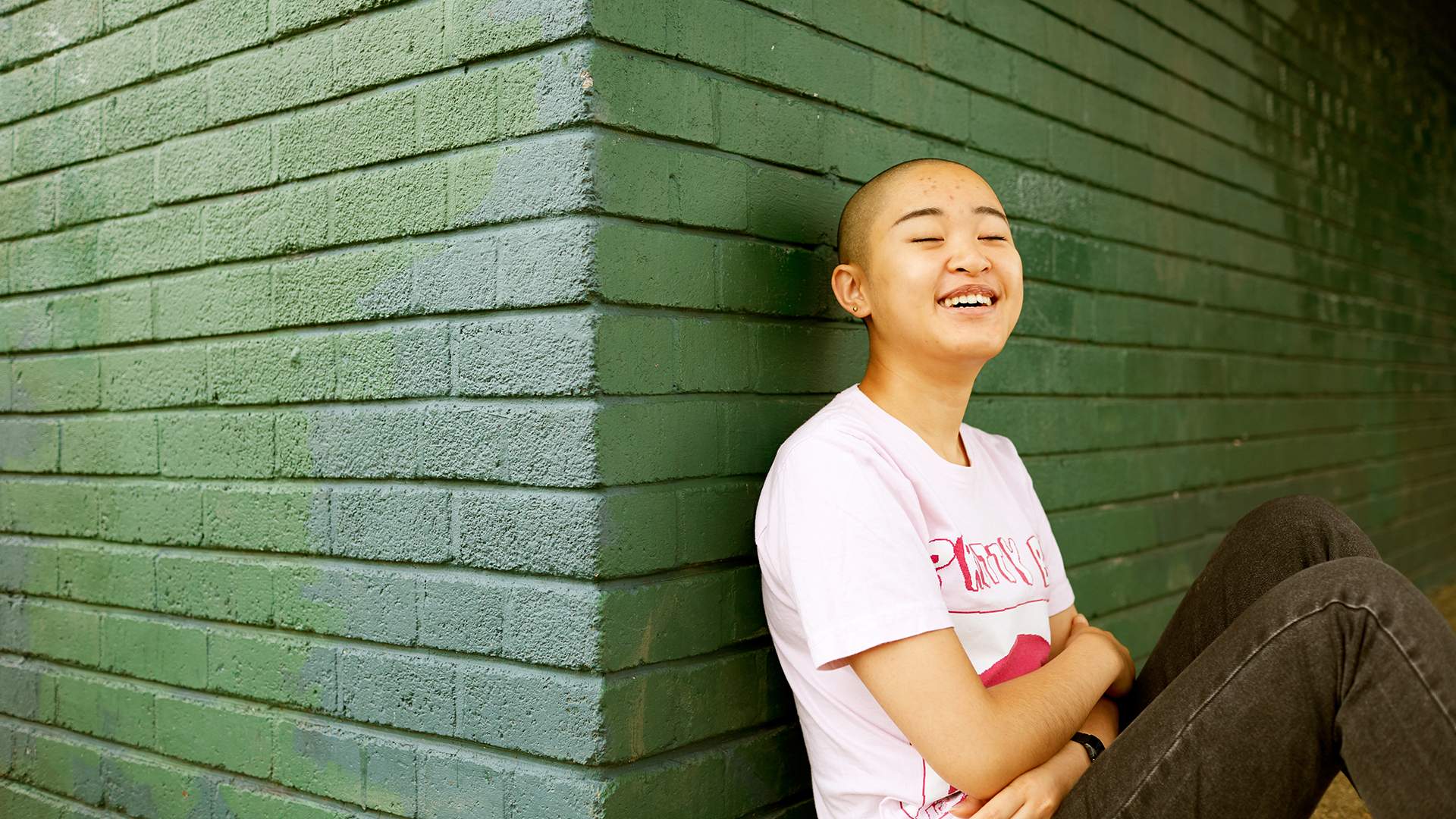 A person leaning against a wall and laughing.