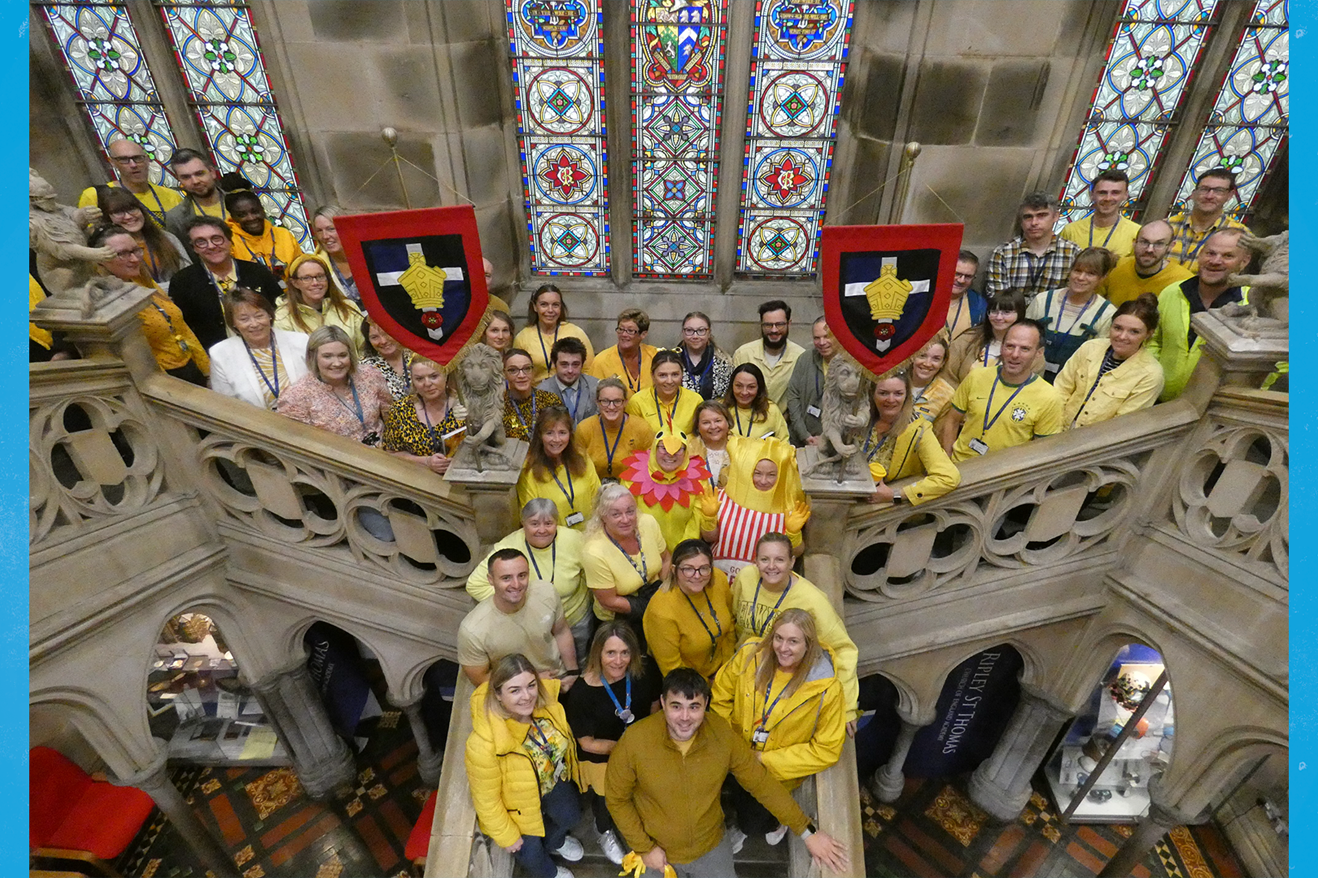 Ripley St Thomas school staff dressed in yellow standing on the stairs in the church.