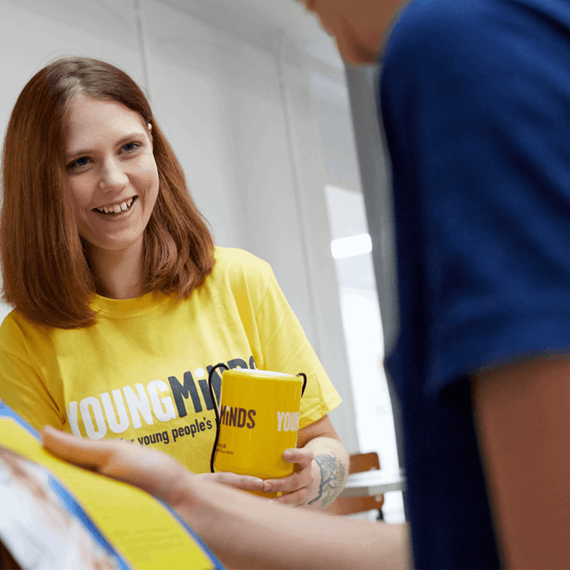 a YoungMinds volunteer wearing yellow YoungMinds shirt smiling in a fundraising event