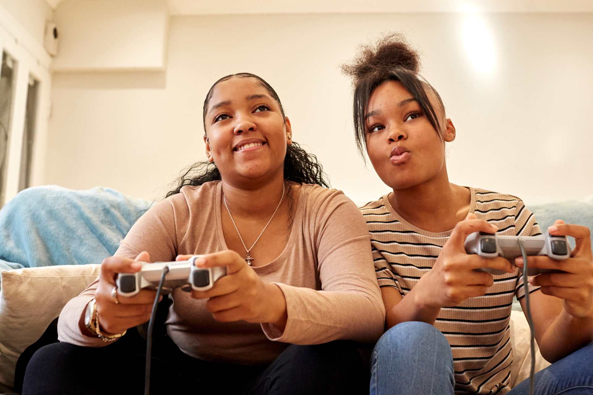 Two young people playing PlayStation on the sofa.