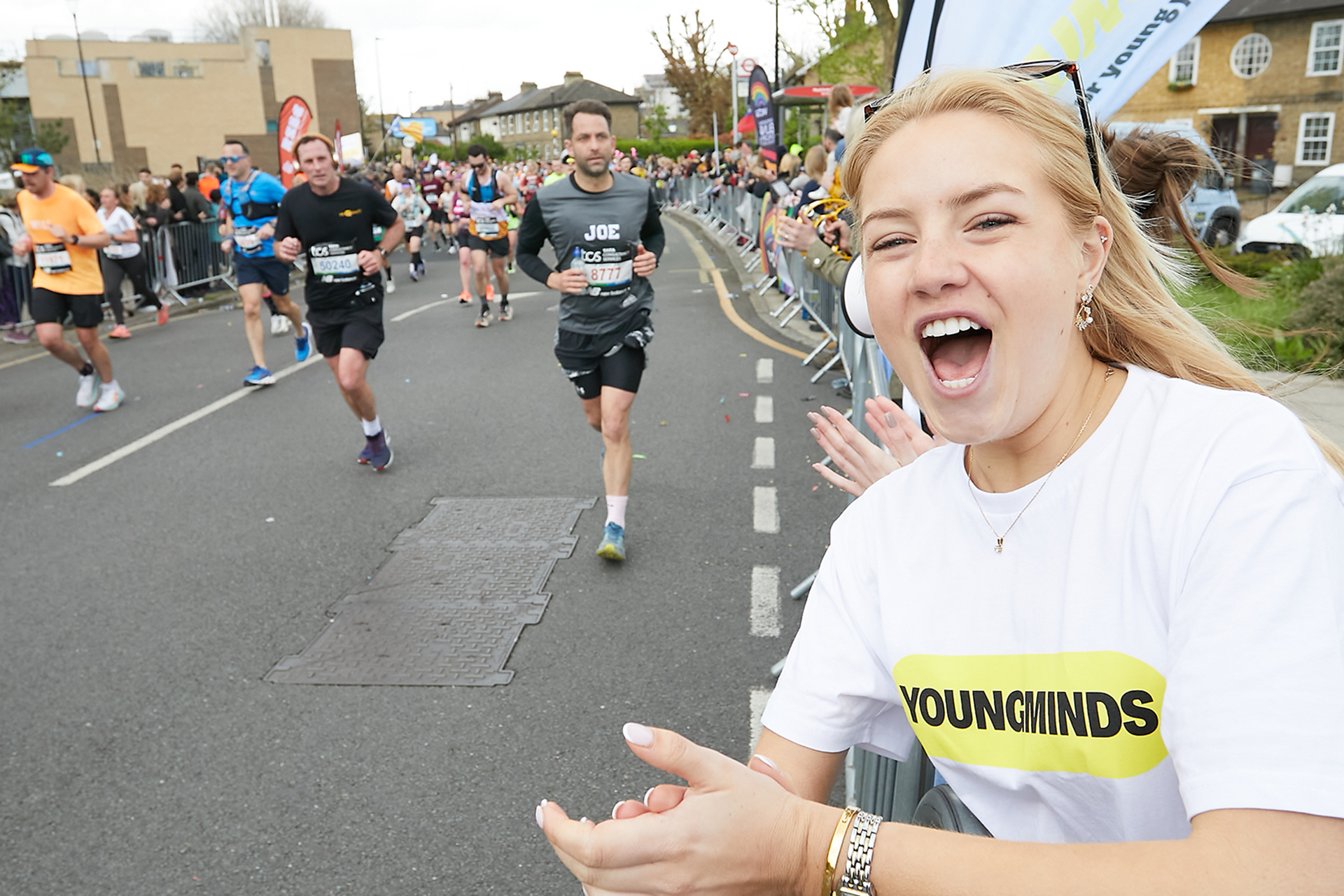 A YoungMinds marathon runner being supported by YoungMinds staff on the side line.