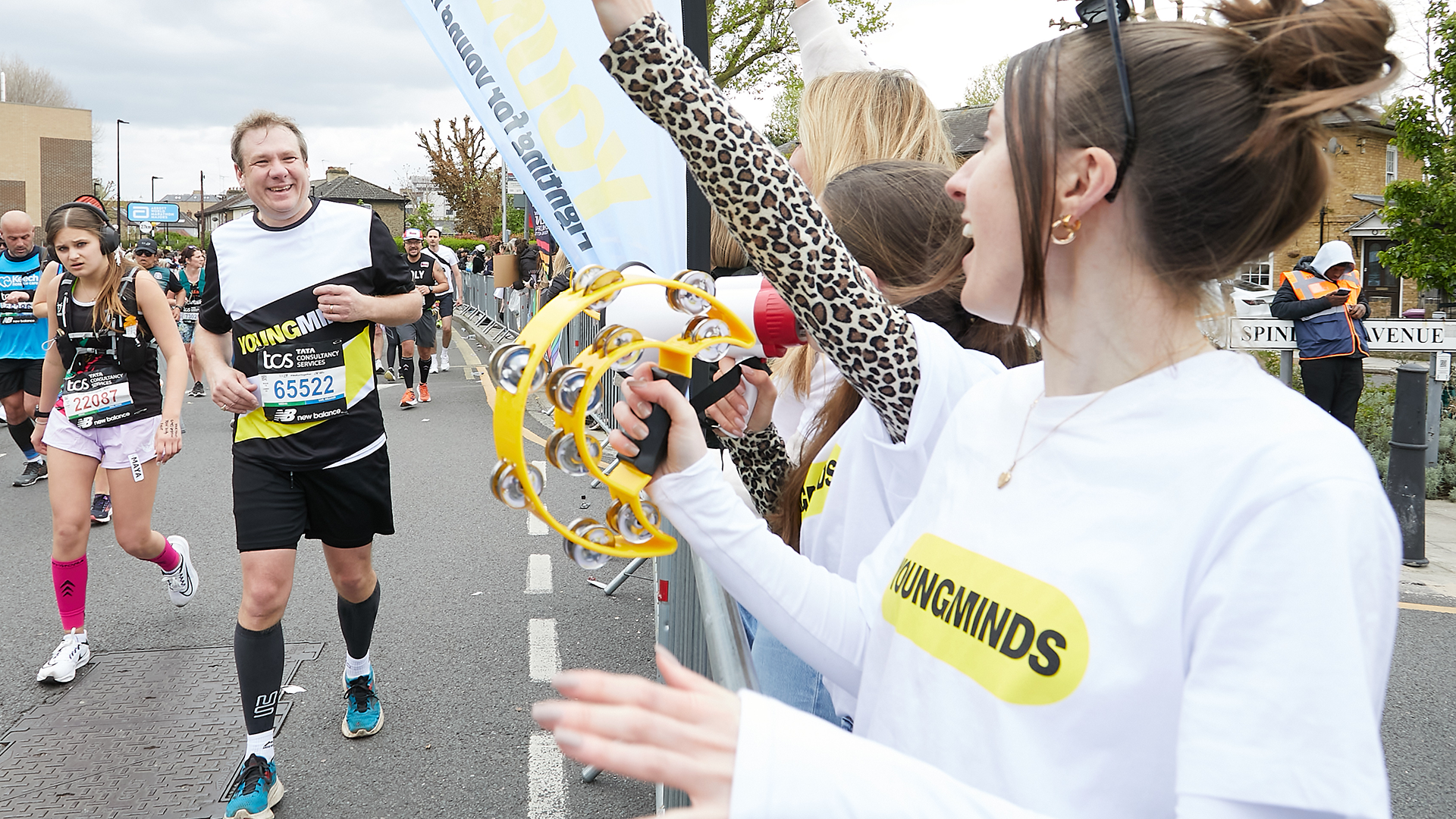 A YoungMinds marathon runner being supported by YoungMinds staff on the side line.