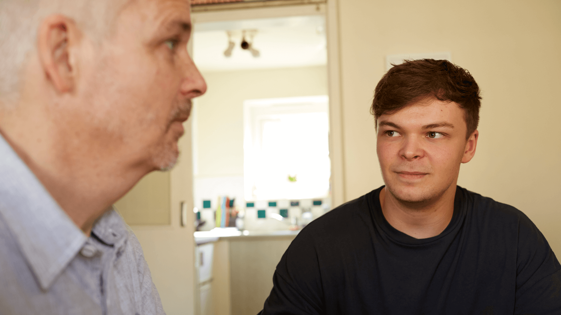 A father and son at home together having a conversation