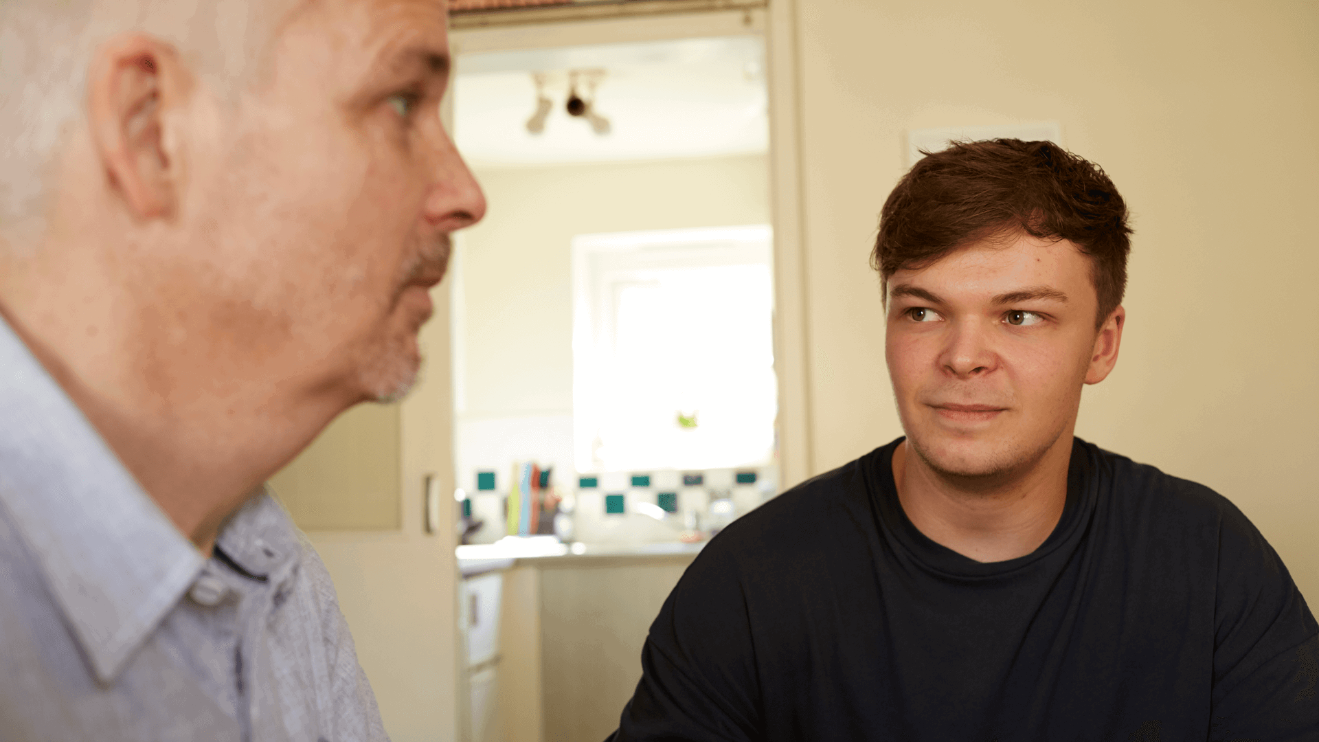 A father and son at home together having a conversation