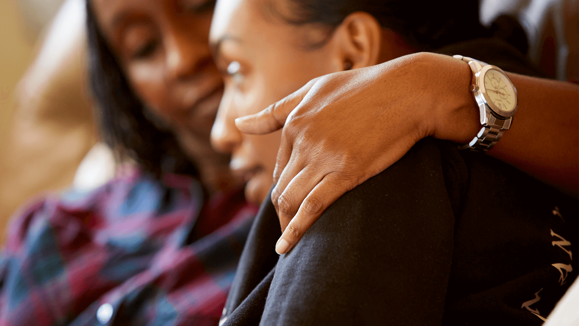 A mother comforts her daughter at their home.