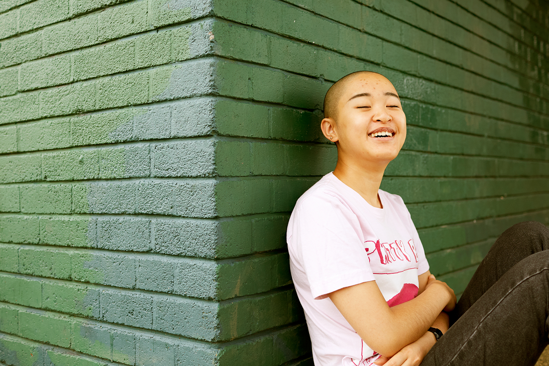 A person leaning against a wall and laughing.