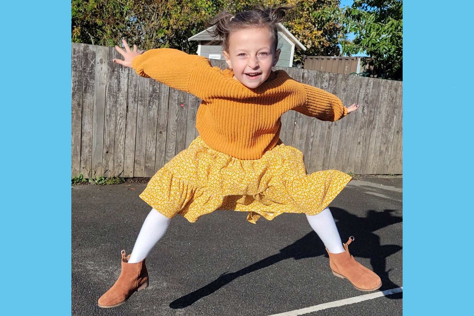 A girl from St Benets Primary School jumps in the playground wearing all yellow.