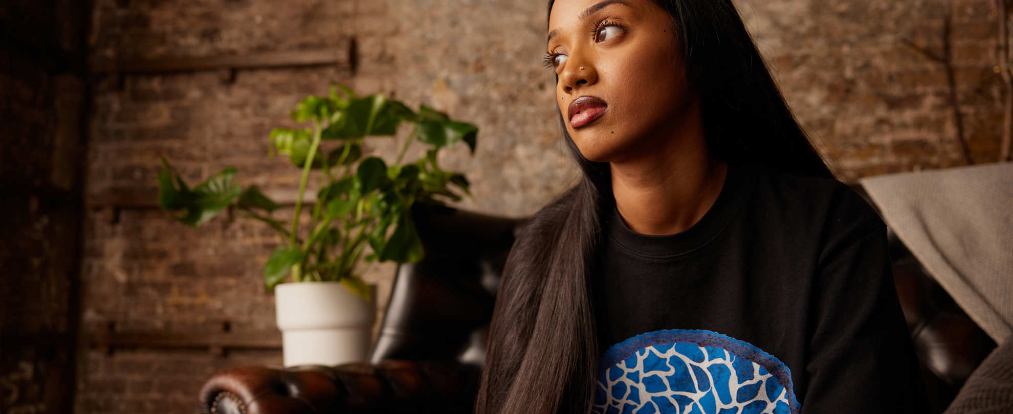 A person thinking, sat on the sofa.