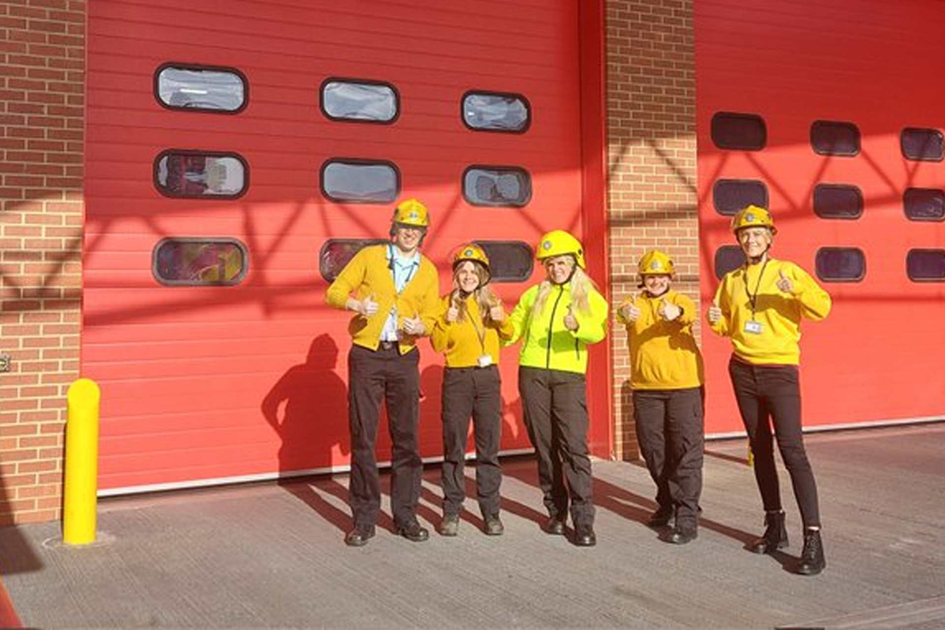 West Yorkshire Fire and Rescue pose in their fire hats wearing yellow.