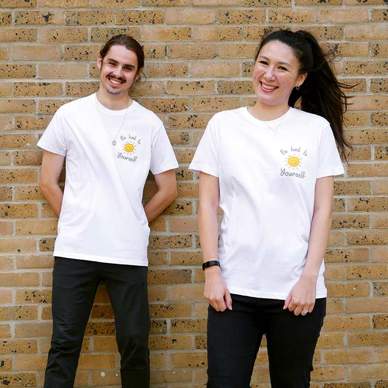 boy and girl smiling wearing YoungMinds shirt with Be kind to yourself text graphics