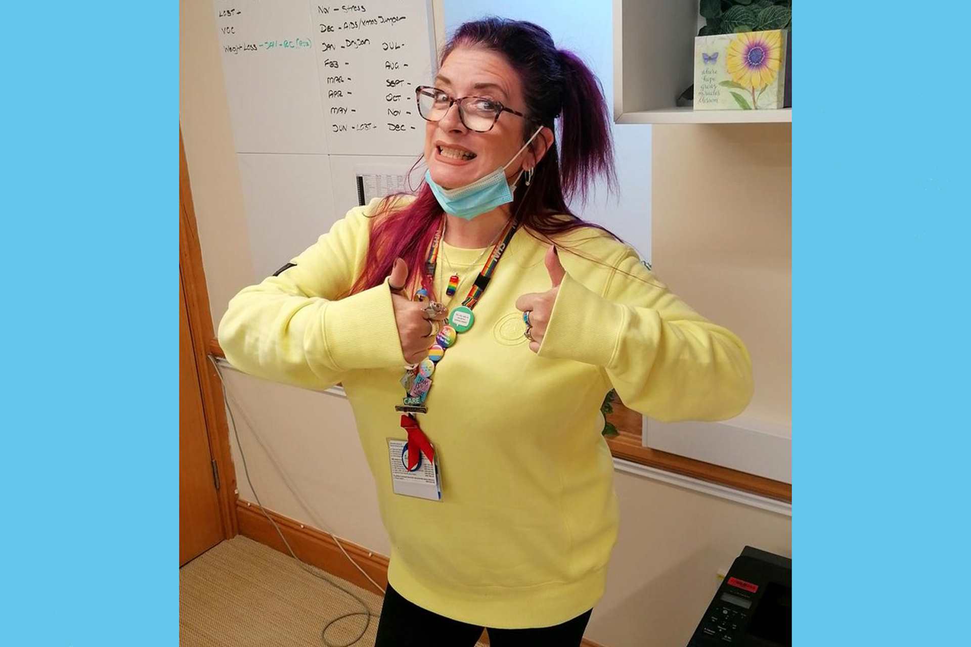 An NHS worker poses in a yellow jumper.