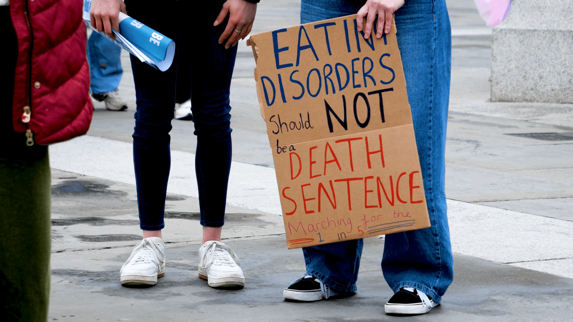 Person holding a sign at the Dump The Scales march 2024. The sign says: 'eating disorders should not be a death sentence. Marching for the one in five.'