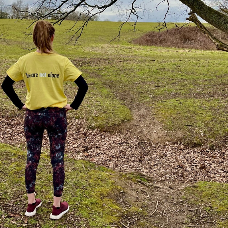 A person in a YoungMinds t-shirt looking out over a field.