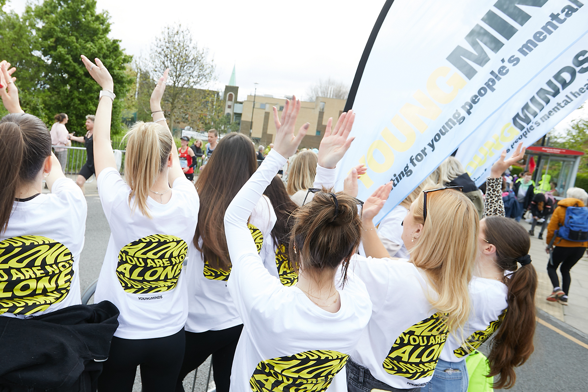 YoungMinds staff cheering marathon runners on from the side line in YoungMinds t-shirts and with YoungMinds banners.