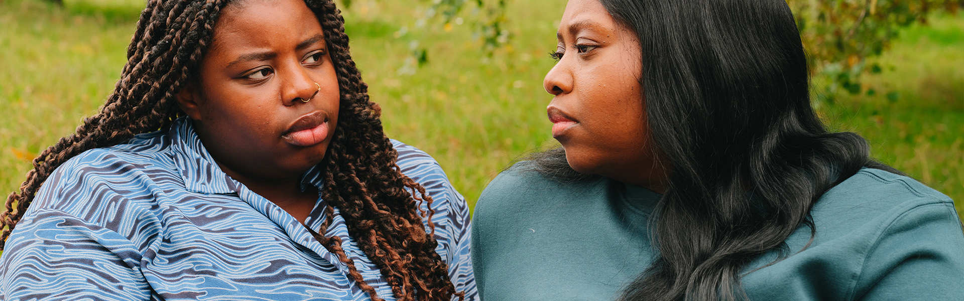 A young Black woman talking about something serious with an older Black woman in the park.