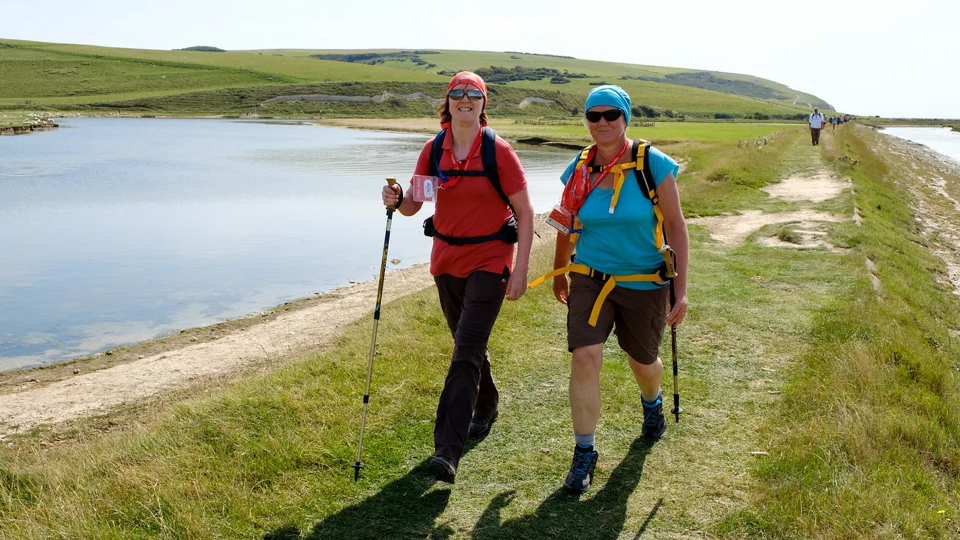 Two people walking through the countryside with hiking sticks