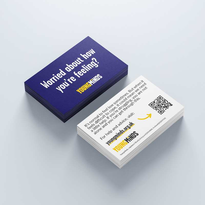 Our dark blue find help business cards sit on a white surface. One pile has the front of the business cards facing upwards with the other pile having the back facing upwards.