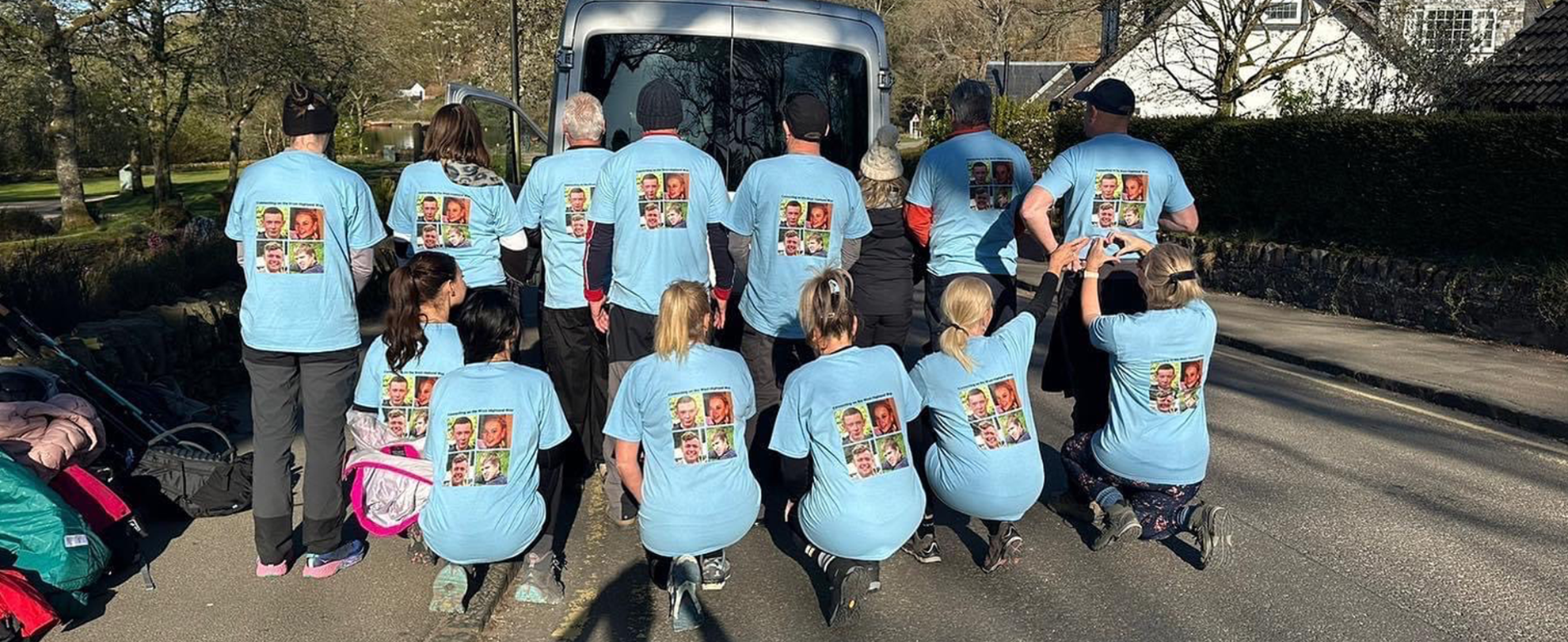 A group picture of 4 Families Walking showing the back of their t-shirts with their loved ones pictures.