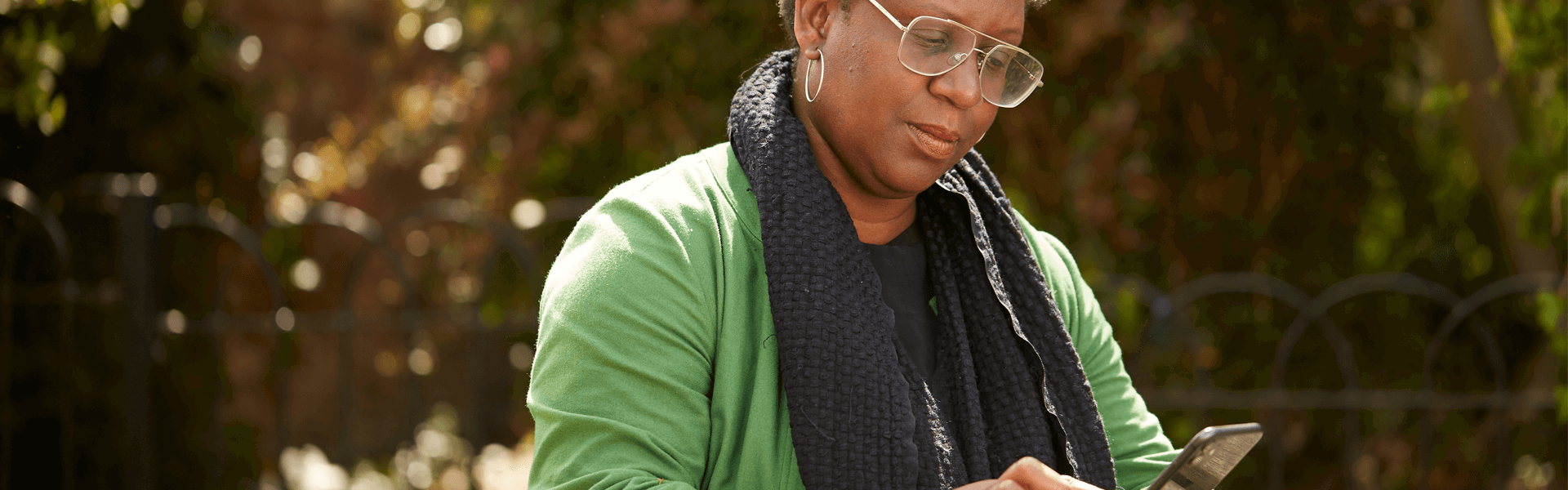 A lady typing on her phone while sitting at a picnic table