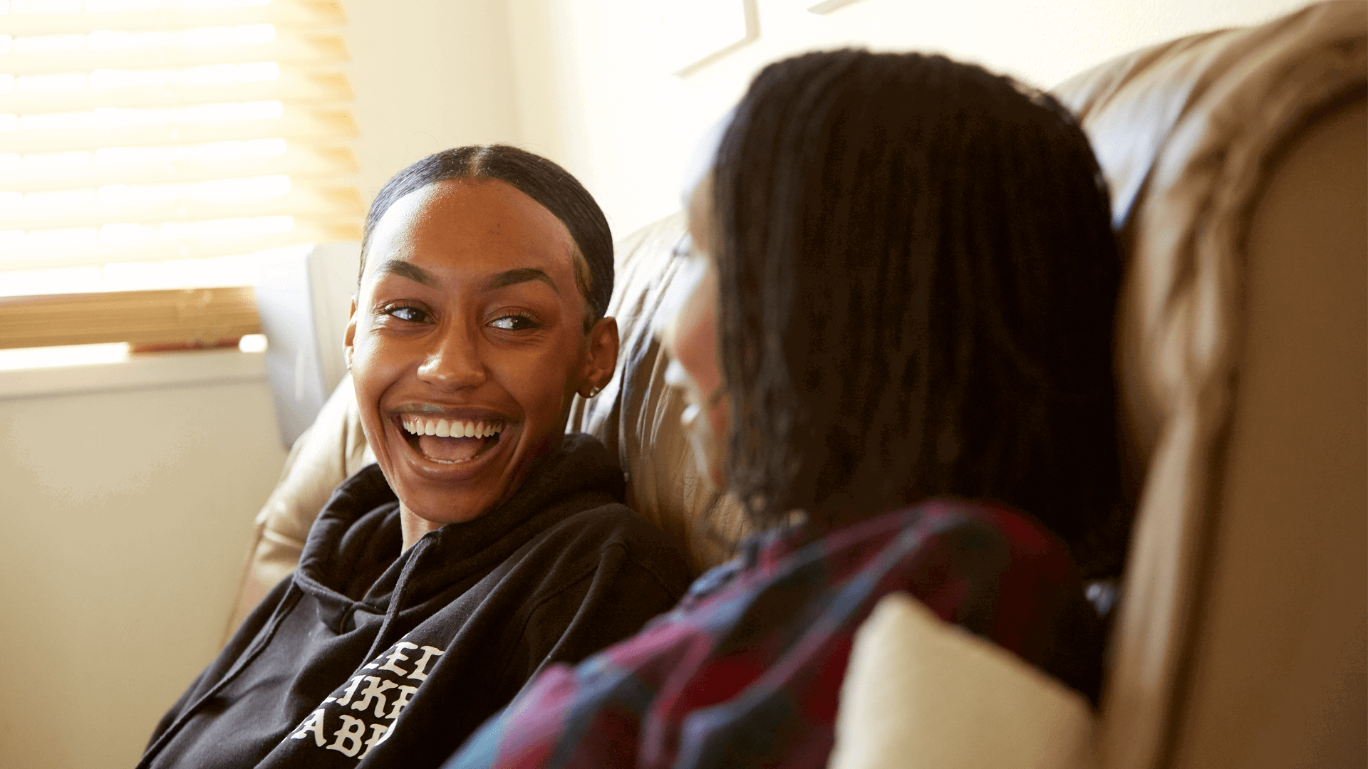 A very happy young girl smiling at her mum on the sofa