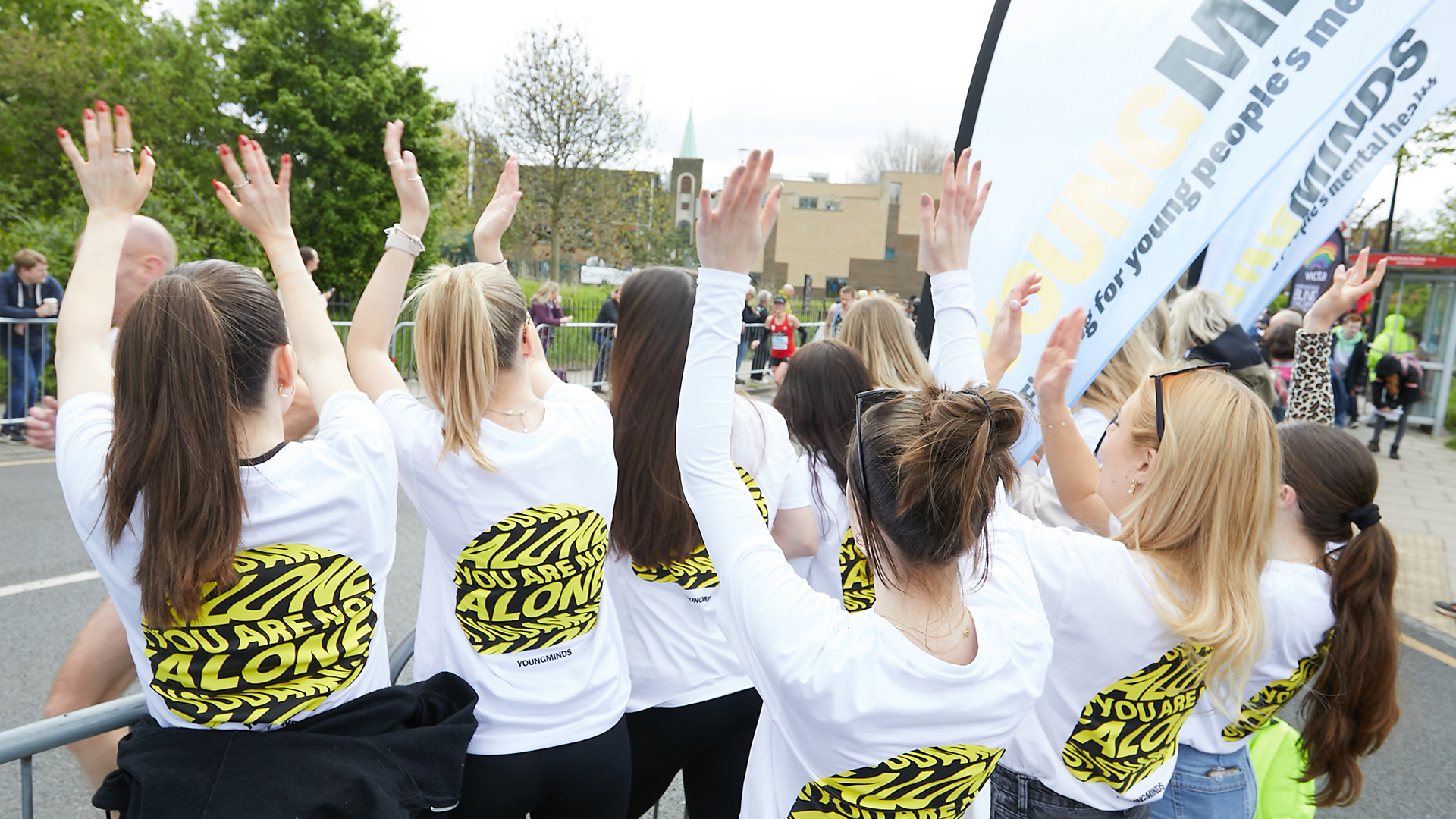 YoungMinds staff cheering marathon runners on from the side line in YoungMinds t-shirts and with YoungMinds banners.