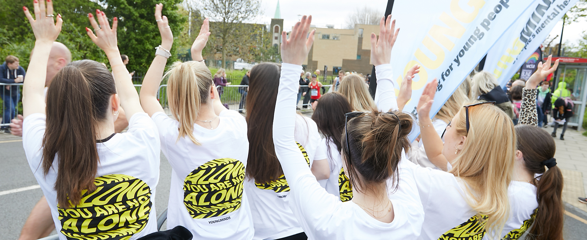 YoungMinds staff cheering marathon runners on from the side line in YoungMinds t-shirts and with YoungMinds banners.
