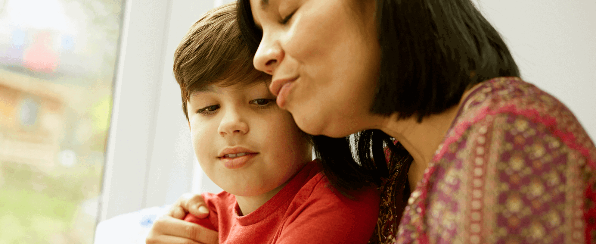 Parent talking to their son with their arm around him.