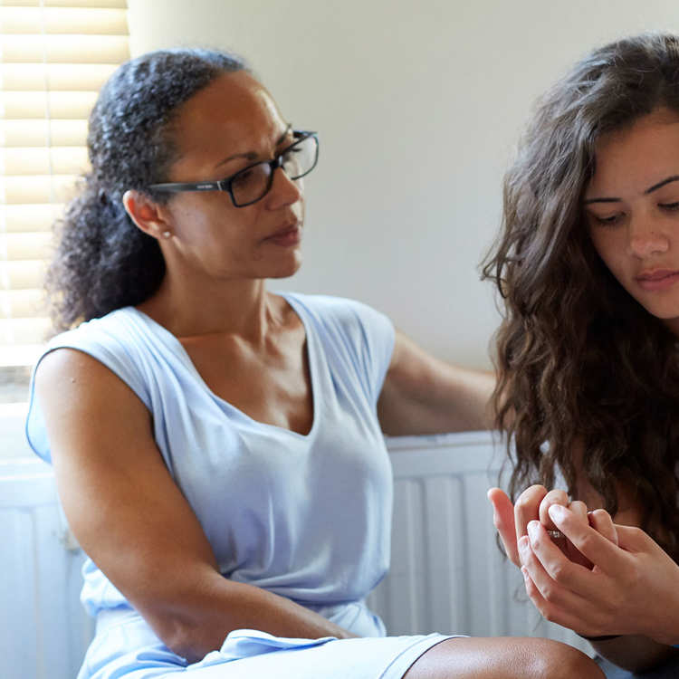 A mother and daughter having a serious discussion at home in front of a radiator