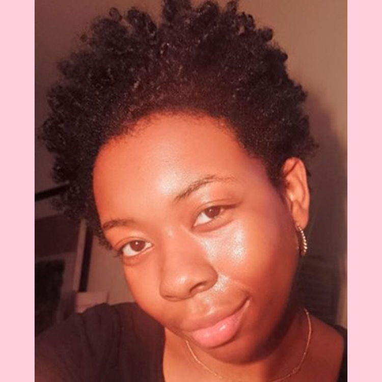 Neka is looking at the camera wearing a necklace and a black tshirt.