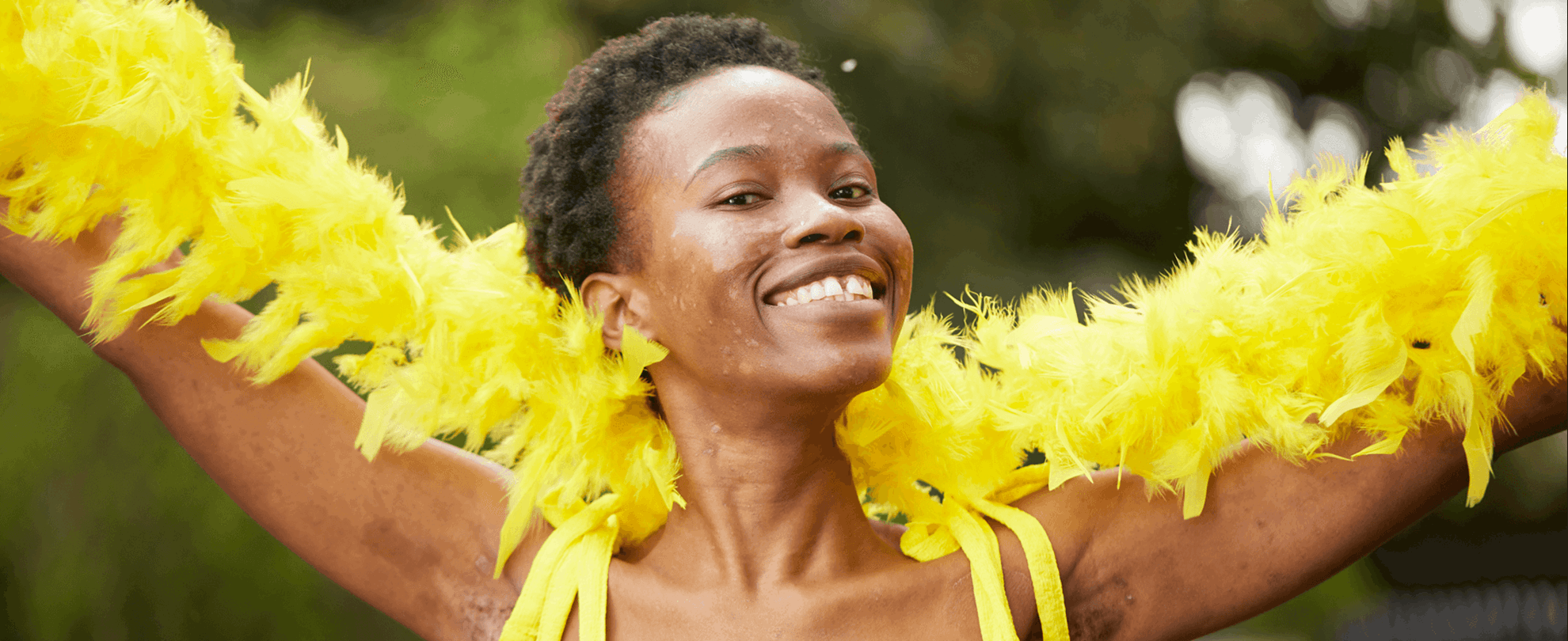 medium shot of a fundraising ambassador wearing yellow dress and yellow feather scarf smiling at the camera