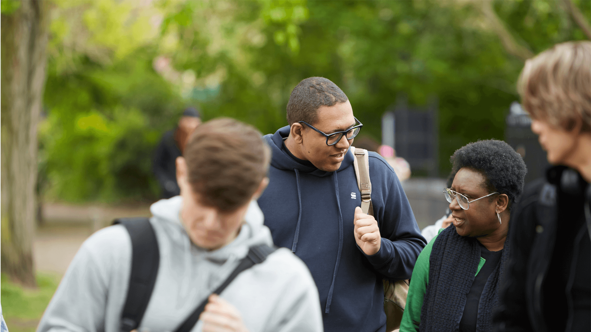 A group of young people talking together as they walk through a college campus.