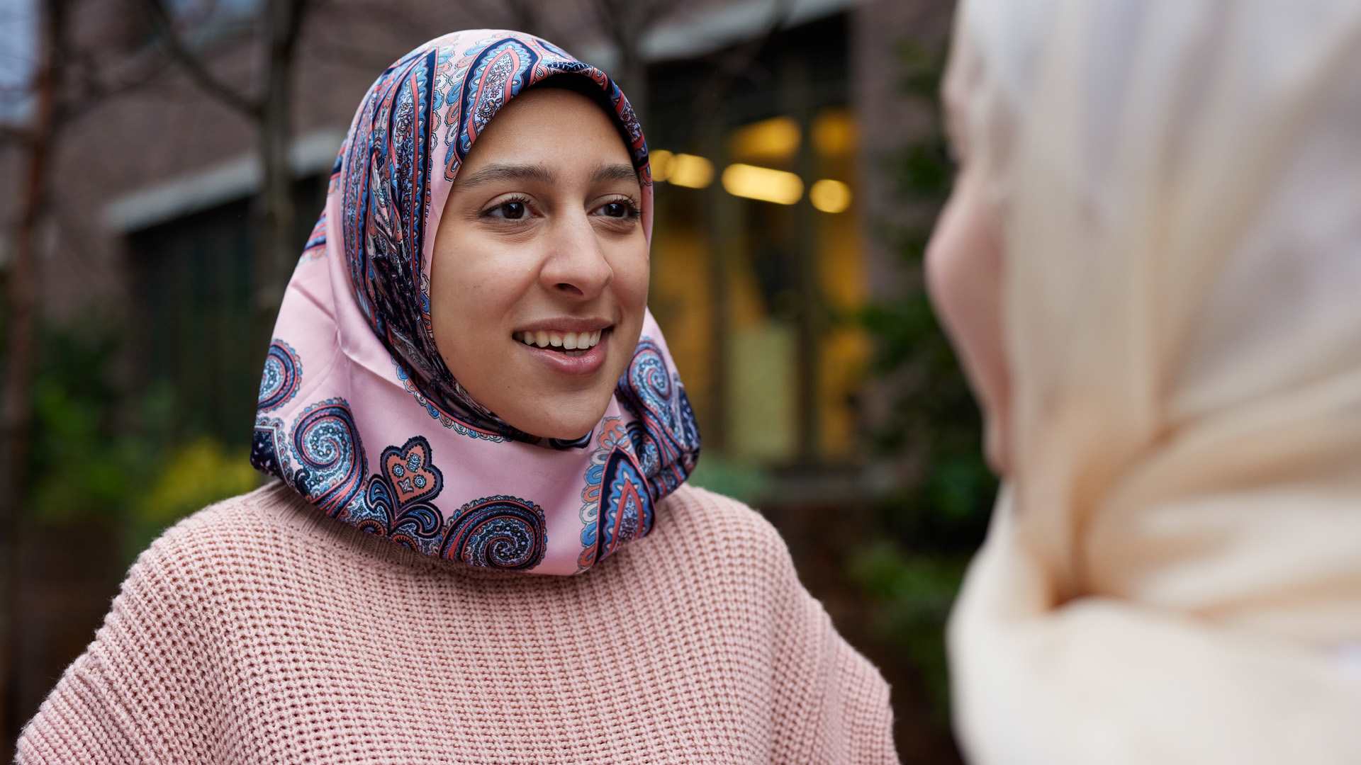 Two young Muslim women in headscarves talking.