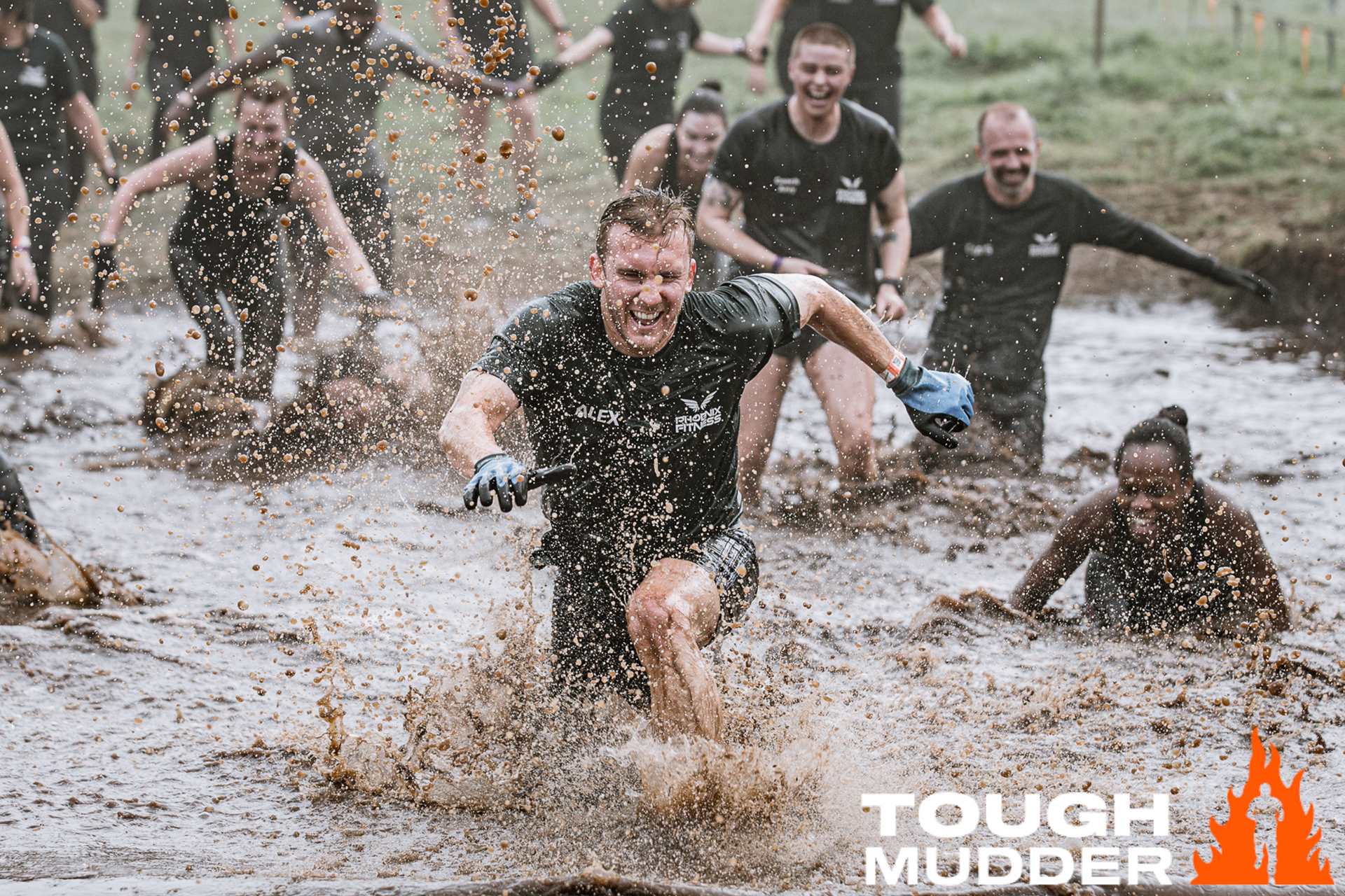 Tough Mudder participants running through mud and laughing