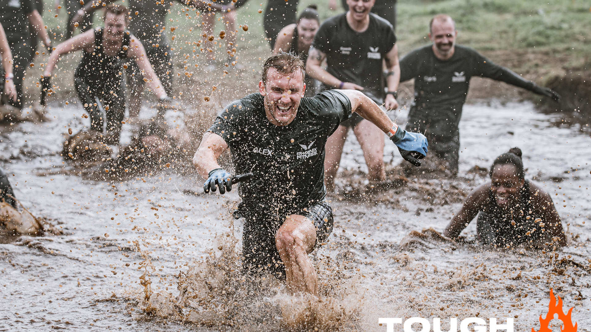 Tough Mudder participants running through mud and laughing