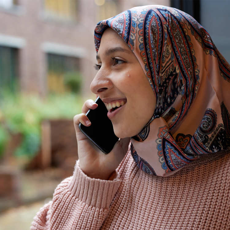 A person wearing a headscarf on the phone.