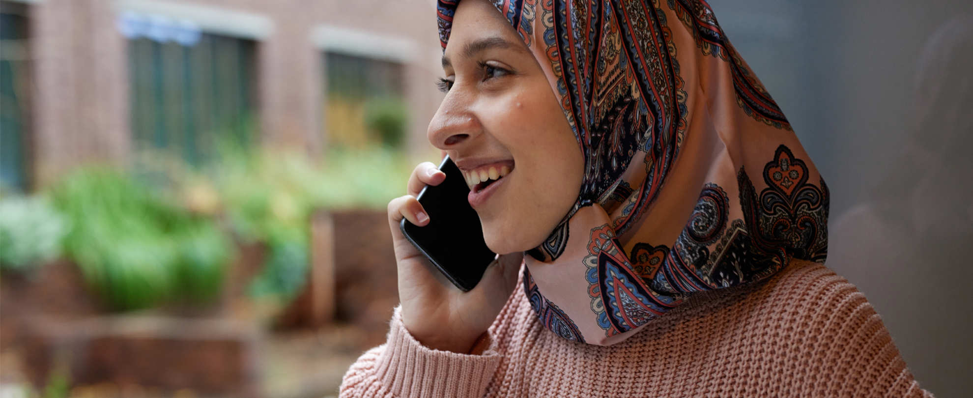 A person wearing a headscarf on the phone.