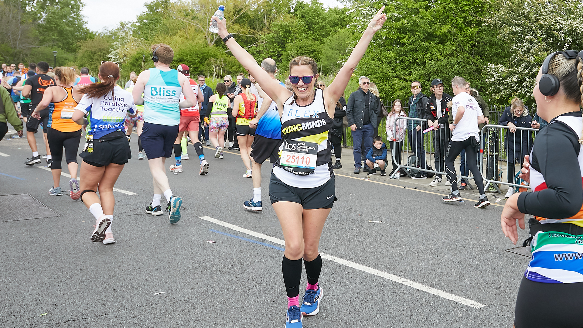 A YoungMinds marathon runner running with their hands in the air and smiling.