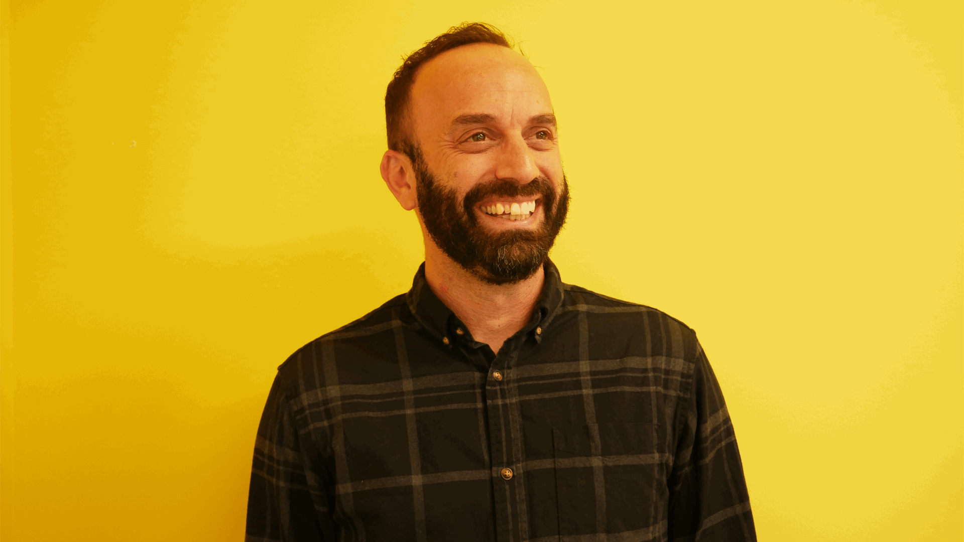 YoungMinds staff member Mike Woolf smiling and against a yellow background