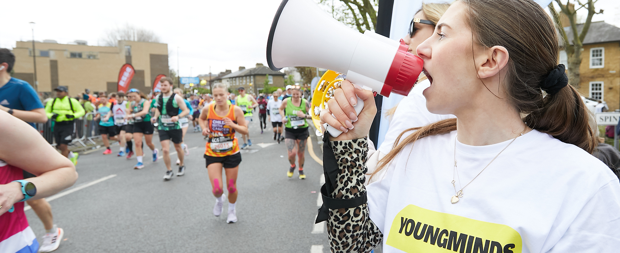 A YoungMinds marathon runner being supported by YoungMinds staff on the side line.
