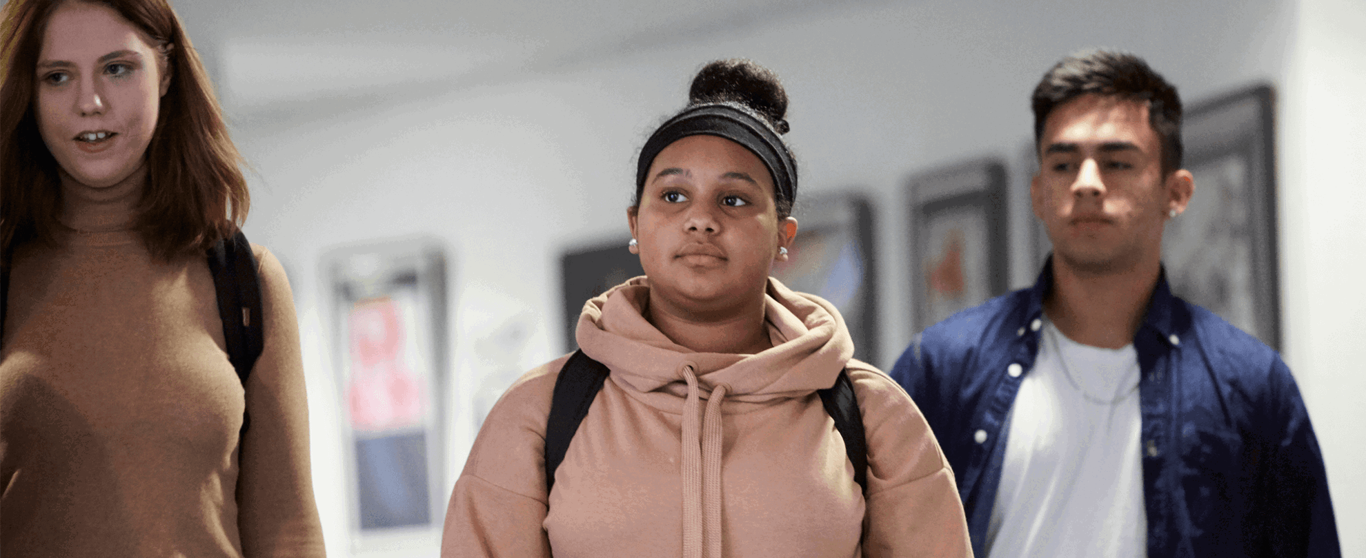 Three students walking down a school corridor.