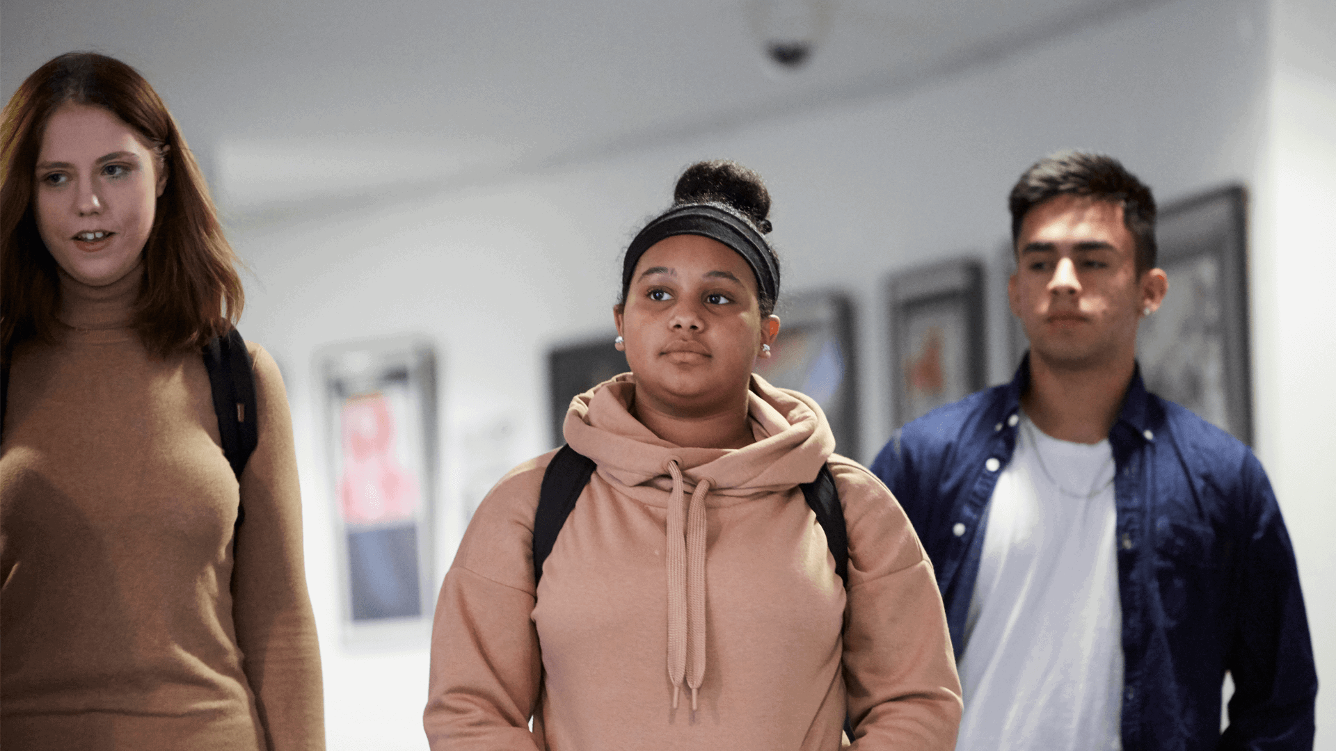 Three students walking down a school corridor.