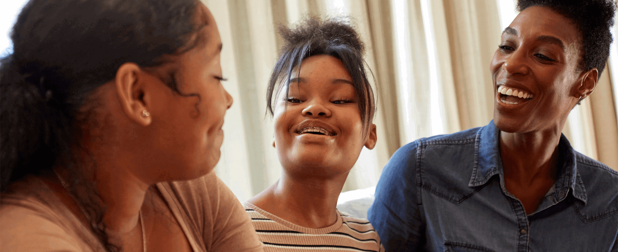 A mother and her two daughters smiling and laughing together.