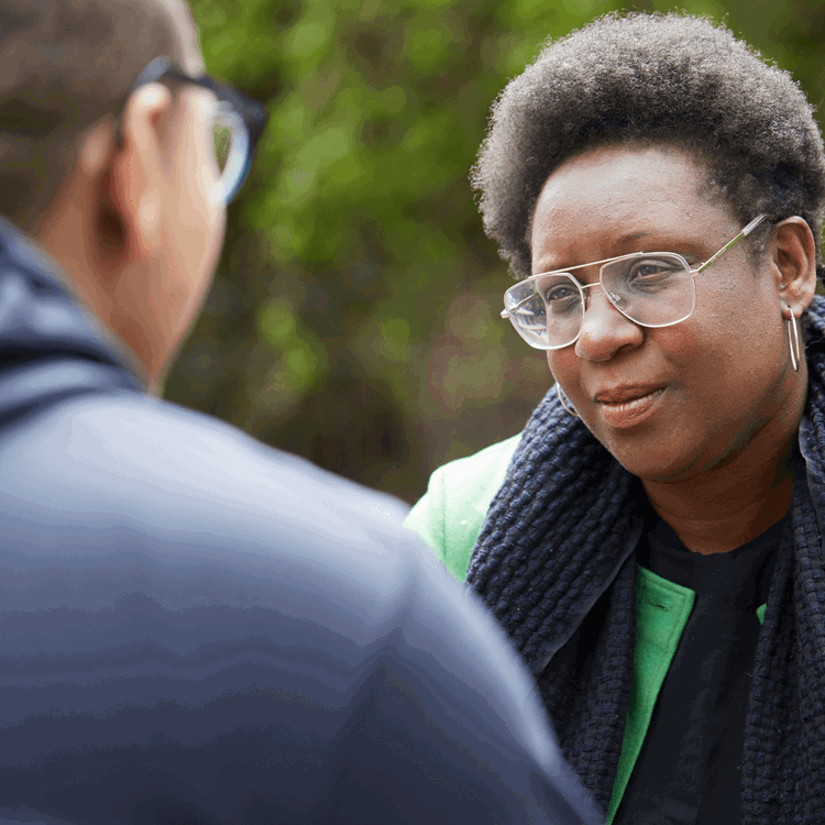 A man and woman look at each other outdoors