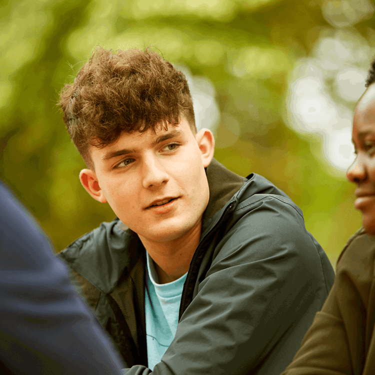 Three young people sitting together in a park.