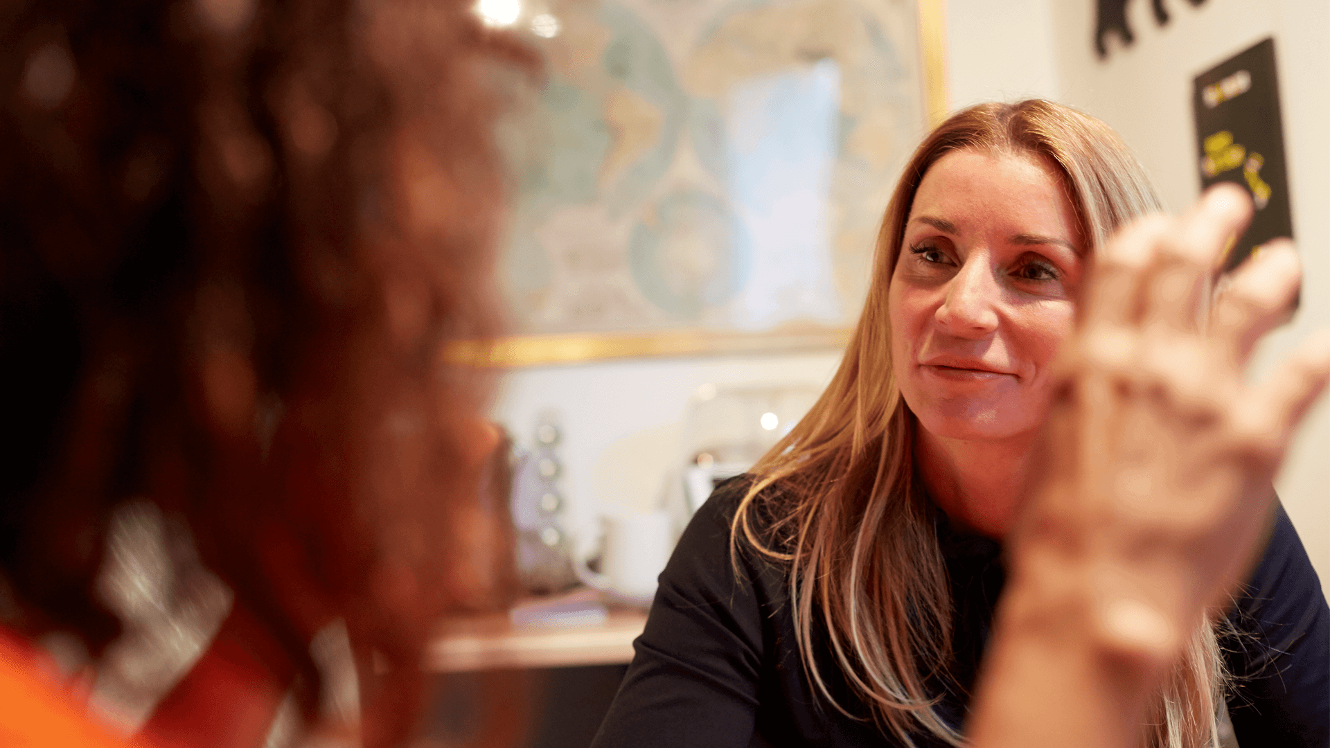 Two women sitting in a room chatting socially 