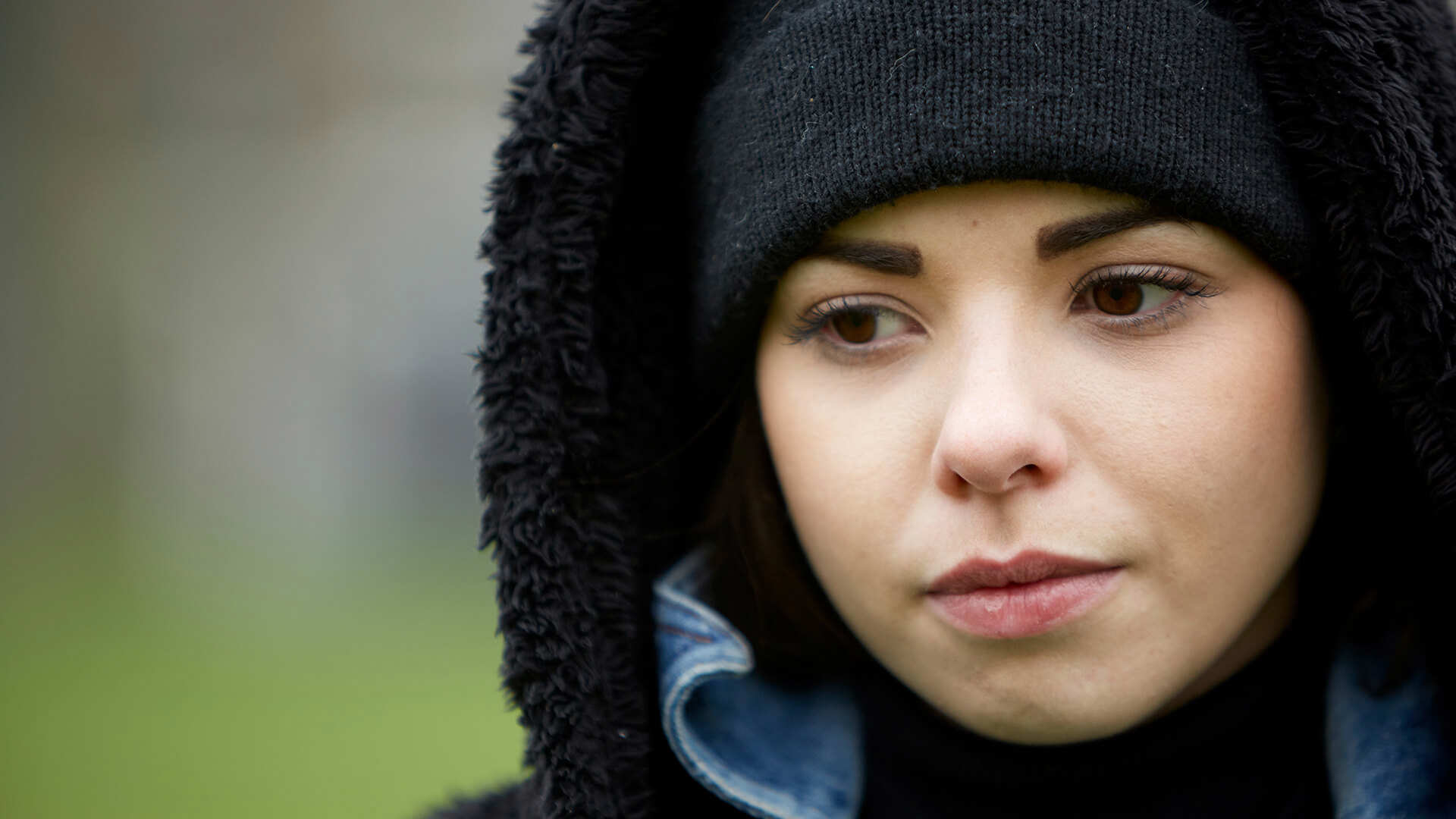close-up-of-a-girl-wearing-black-beanie-looking-worried-with-eyes-looking-down