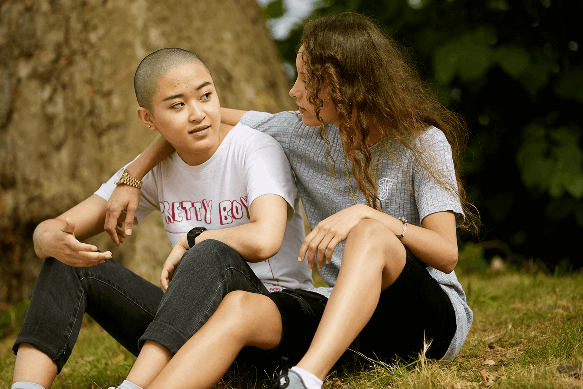 Two young people sitting in the grass together.