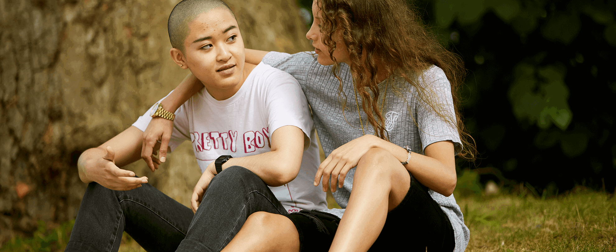 Two young people sitting in the grass together.