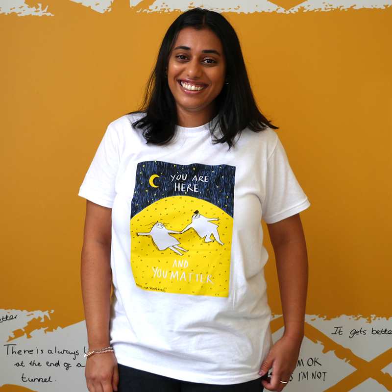 A woman smiling wearing our Rubyetc bespoke 'You are here and you matter' graphic #HelloYellow T-shirt