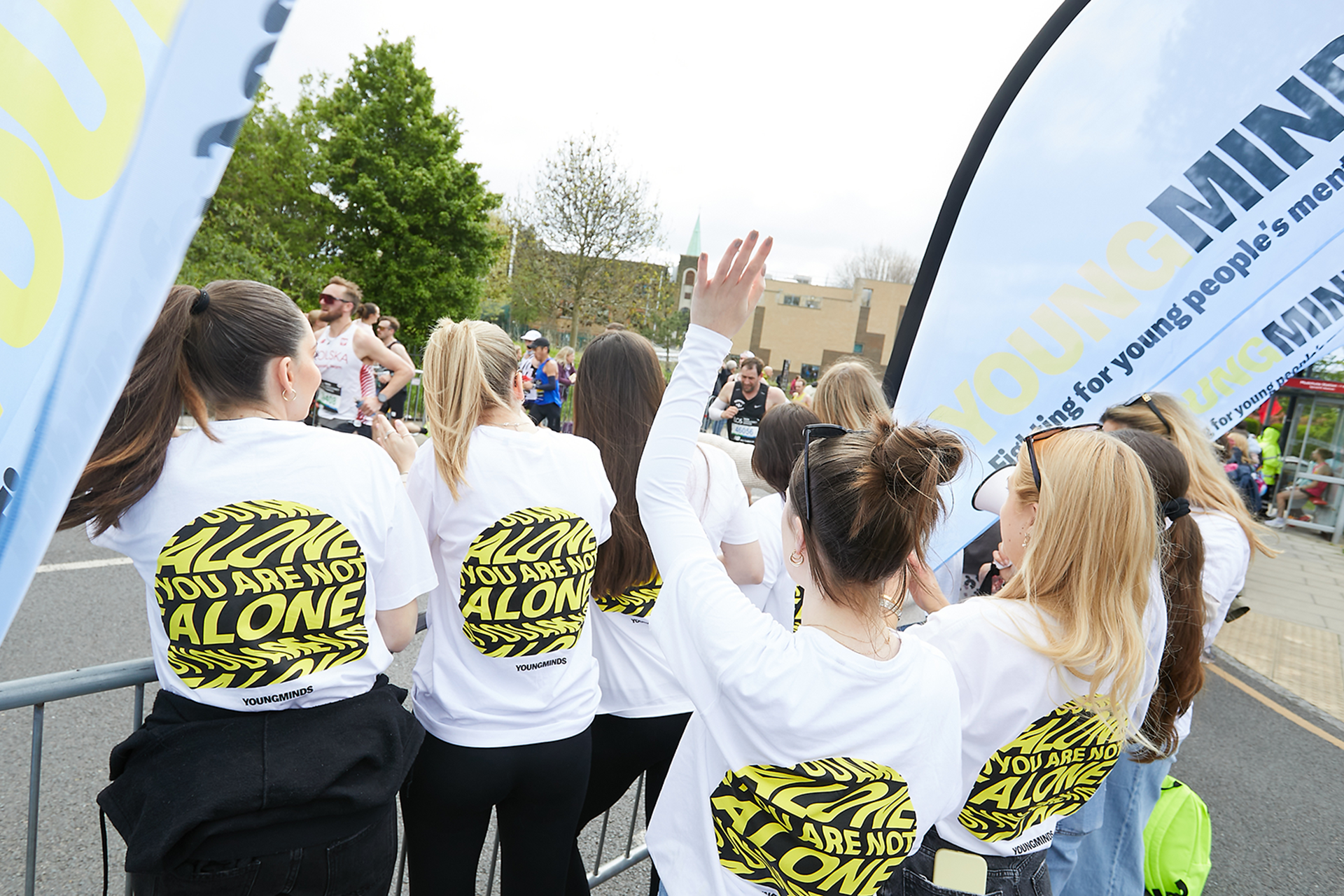 YoungMinds staff cheering marathon runners on from the side line in YoungMinds t-shirts and with YoungMinds banners.